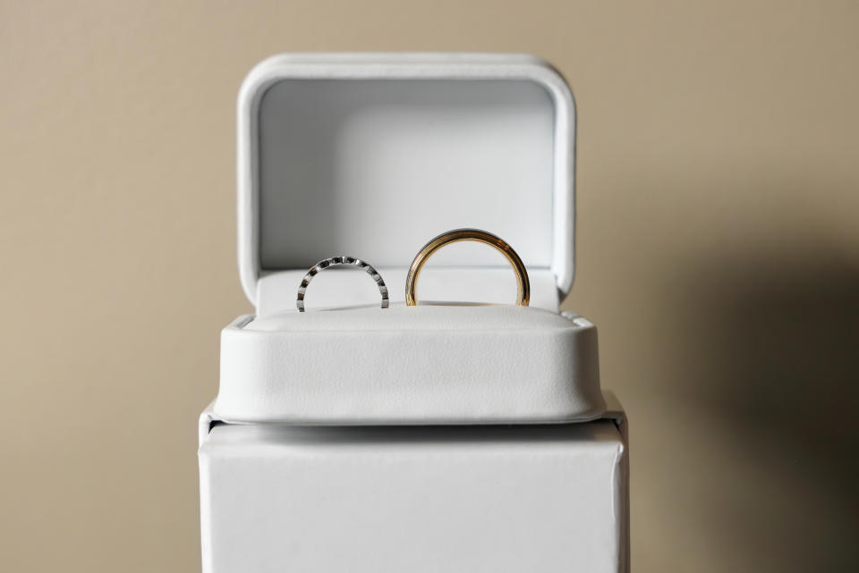 Two wedding rings in a white jewelry box, one with a thin band and the other with a thicker band