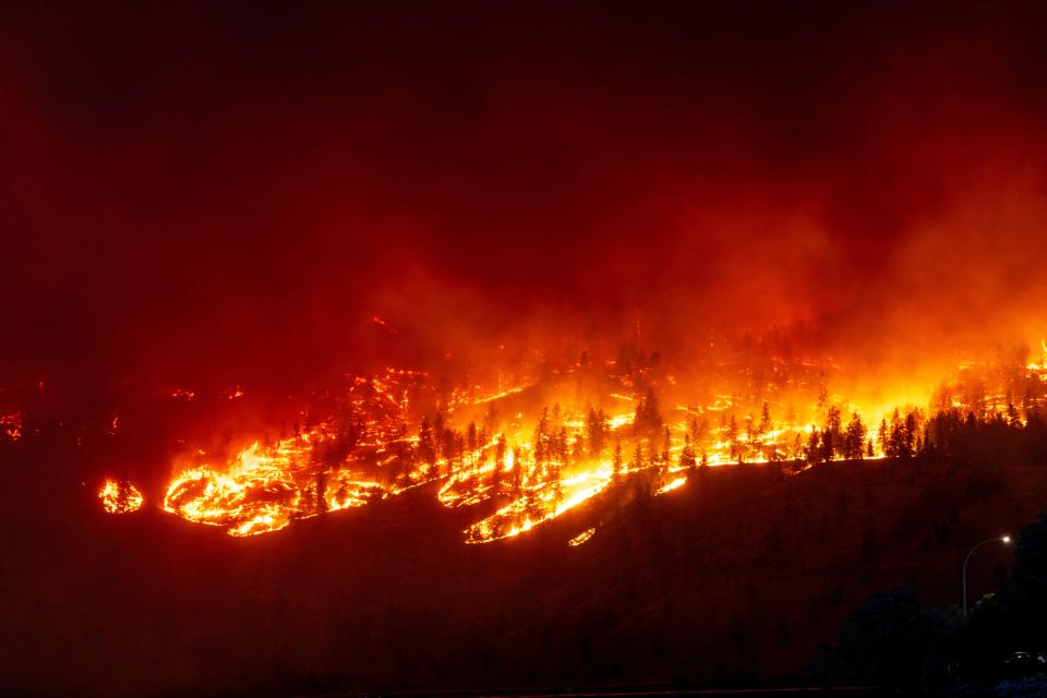 The McDougall Creek wildfire burns in the hills West Kelowna, British Columbia, Canada, on August 17, 2023, as seen from Kelowna. Evacuation orders were put in place for areas near Kelowna, as the fire threatened the city of around 150,000. Canada is experiencing a record-setting wildfire season, with official estimates of over 13.7 million hectares (33.9 million acres) already scorched. Four people have died so far. (Photo by Darren HULL / AFP) (Photo by DARREN HULL/AFP via Getty Images)