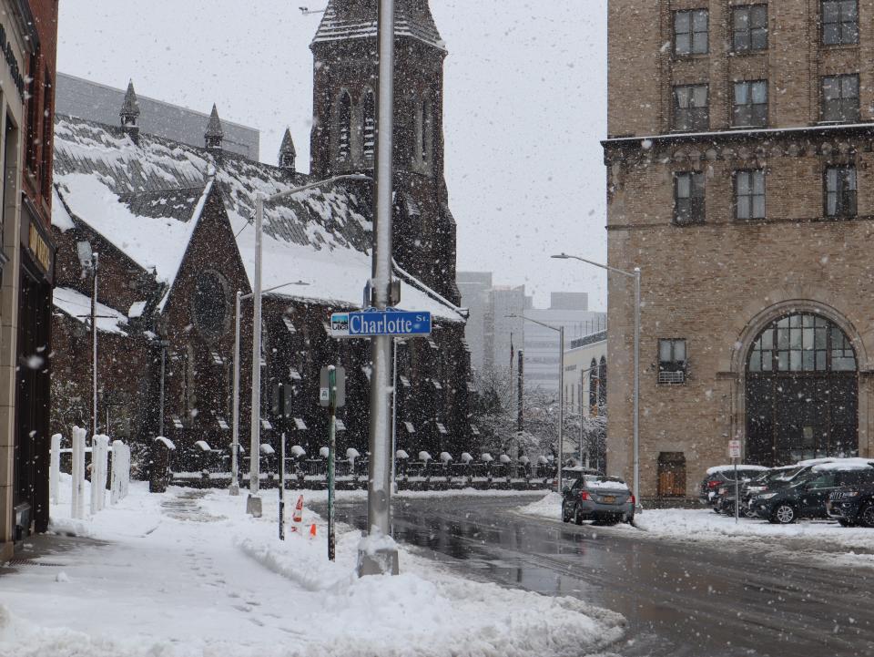 Snow continues to fall Tuesday morning at the corner of Charlotte and Elizabeth Streets in Utica during a winter storm on April 19, 2022.