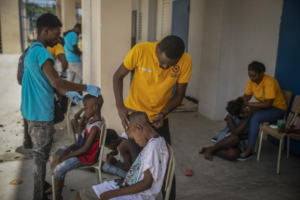 Workers of the NGO known by the acronym OCCED'H cut the hair of children forced to leave their homes in Cite Soleil due to clashes between armed gangs, at a school turned into a makeshift in Port-au-Prince, Haiti, Saturday, July 23, 2022. (AP Photo/Odelyn Joseph)