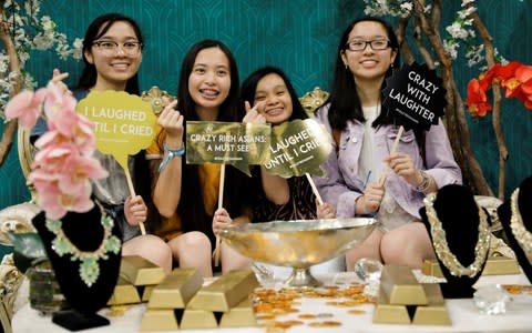 Attendees pose for a picture at a booth promoting the new movie "Crazy Rich Asians" - Credit:  MIKE BLAKE