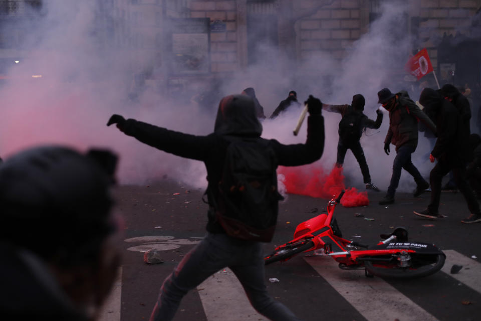 Youths throw items at police forces during a demonstration in Paris, Thursday, Dec. 5, 2019. Small groups of protesters are smashing store windows, setting fires and hurling flares in eastern Paris amid mass strikes over the government's retirement reform. (AP Photo/Thibault Camus)