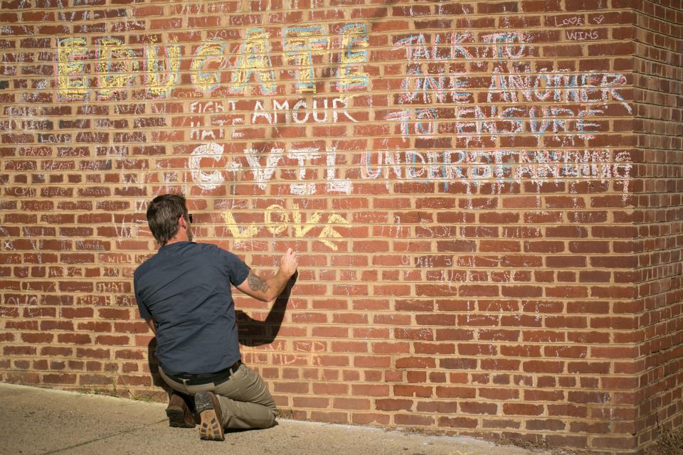 <p>A man adds on August 10, 2018 to the hand-written chalk messages that line the walls outside of the buildings where one year ago, Heather Heyer was killed by a speeding vehicle driven by a white supremacist as she was protesting the Unite The Right rally in Charlottesville, Va. (Photo: Logan Cyrus/AFP/Getty Images) </p>