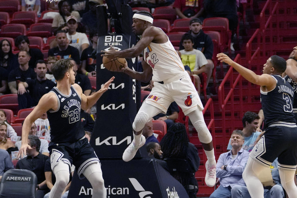 Miami Heat forward Jimmy Butler (22) looks to pass the ball as San Antonio Spurs forward Zach Collins (23) and forward Keldon Johnson (3) defend during the first half of an NBA basketball game Saturday, Dec. 10, 2022, in Miami. (AP Photo/Lynne Sladky)