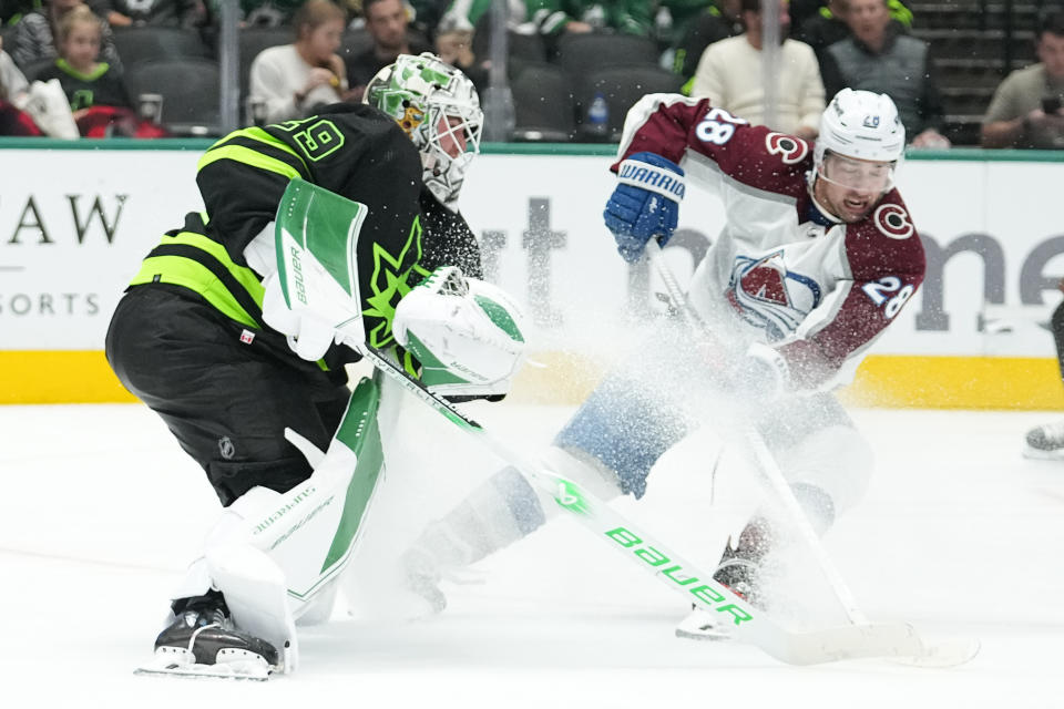 Dallas Stars goaltender Jake Oettinger, left, leaves his crease to defend against Colorado Avalanche left wing Miles Wood during the second period of an NHL hockey game, Saturday, Nov. 18, 2023, in Dallas. (AP Photo/Julio Cortez)