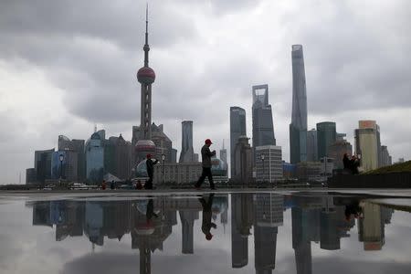 People walk on the bund in front of the financial district of Pudong in Shanghai, China March 9, 2016. REUTERS/Aly Song