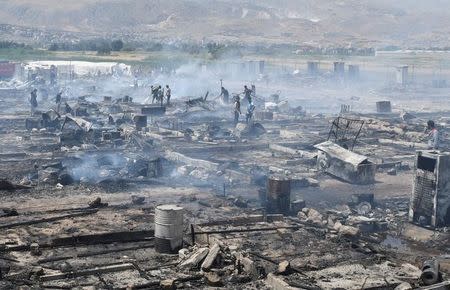 Civil defence members and civilians put out fire at a camp for Syrian refugees near the town of Qab Elias, in Lebanon's Bekaa Valley, July 2, 2017. REUTERS/Hassan Abdallah