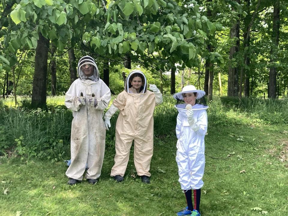 Anton Zeitlinger-Fontana, Isabella Funderburg and Owen Patch show off the protective equipment that students at Knowlton academy use when working closely with the school beehive.