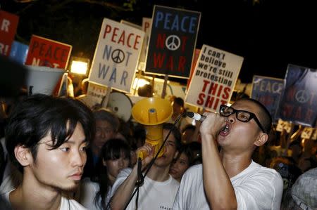 A protester shouts slogans as people holds placards during a demonstration against Japan's Prime Minister Shinzo Abe's security-related legislation outside the parliament building in Tokyo July 16, 2015. REUTERS/Thomas Peter