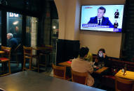 People dine at a restaurant as France's President Emmanuel Macron gives an address on television, in Saint jean de Luz, southwestern France, Wednesday, Oct. 14, 2020. Macron’s office says France will restore a state of health emergency that expired on July 10. There are no additional measures that come into force with the move announced Wednesday, but it will allow the French government to enforce stricter measures in the future, either locally or nationally. (AP Photo/Bob Edme)