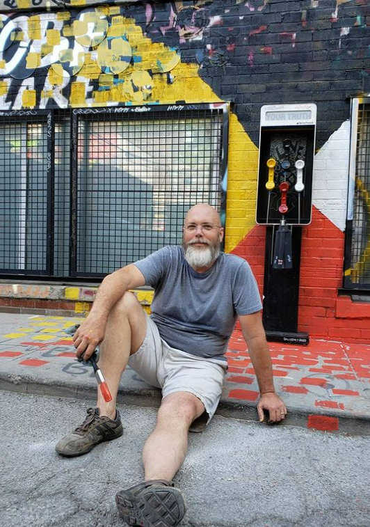 Canadian multimedia artist Mike Salisbury poses for a portrait in front of his sculpture "Truth Phone," located on Graffiti Alley in Toronto.