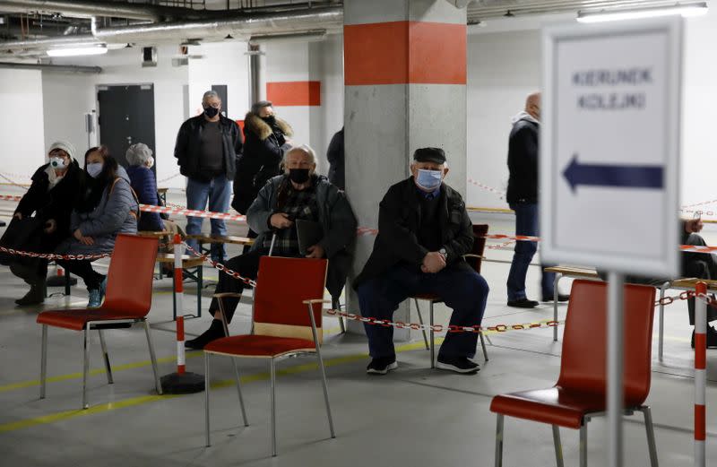 FILE PHOTO: People wearing protective masks wait in line at the coronavirus disease (COVID-19) vaccine centre situated at a temporary hospital organised at the National Stadium in Warsaw