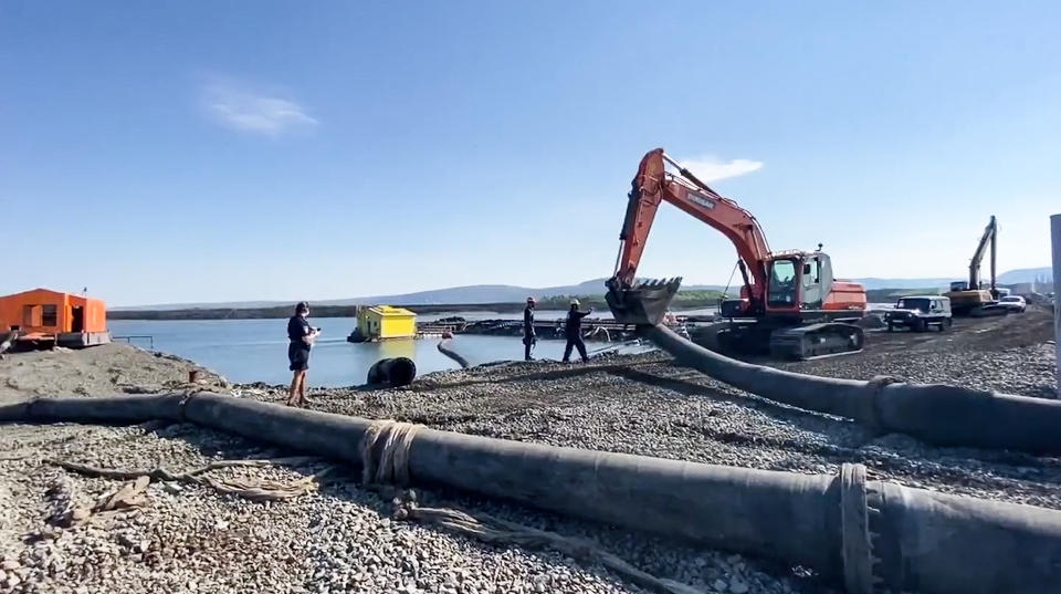 In this photo released Sunday June 28, 2020, by Novaya Gazeta, showing what the report is an excavator disassembling a pipe from a Norilsk Nickel enrichment plant with water gushing into a river which also runs into the lake near Norilsk, 2,900 kilometers (1,800 miles) northeast of Moscow, Russia. Russia's main criminal investigation body has launched a probe after a report that a nickel-processing plant was pumping water contaminated with heavy metals into the Arctic tundra. (Elena Kostyuchenko, Novaya Gazeta via AP)