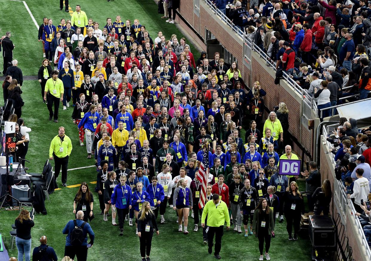 Milan's Angelina Pena carries the American Flag as the girls lead in the grand march with boys Division 1, 2, 3 and 4 Friday, March 1, 2024 at the MHSAA State Individual Wrestling Championships at Ford Field in Detroit.