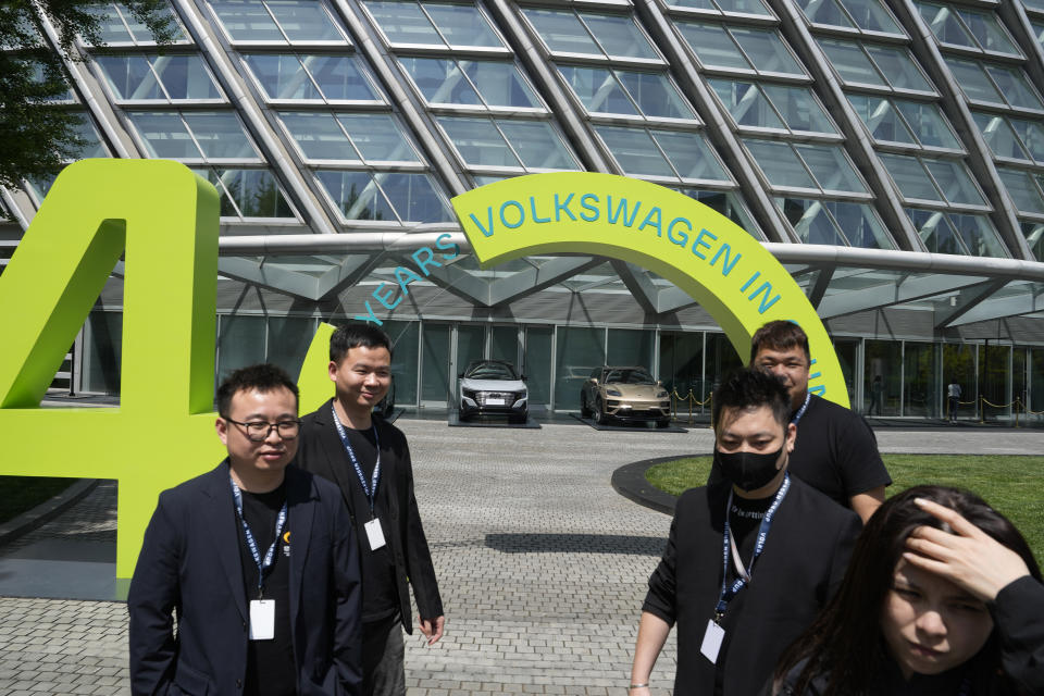 Workers stand near a sign marking Volkswagen's 40 years (in China) in Beijing, Wednesday, April 24, 2024. Foreign automakers have been caught flat-footed in China by an electric vehicle boom that has shaken up the market over the last three years. That has left manufacturers like Volkswagen scrambling to develop new models for a very different market than at home. (AP Photo/Ng Han Guan)