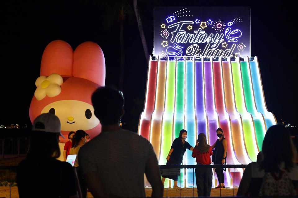 SINGAPORE - DECEMBER 16: People wearing protective mask takes a photo with a Sanrio character', My Melody during the Sentosa's festive light-up, Island Lights with Sanrio characters at Siloso beach, Sentosa on December 16, 2020 in Singapore. As of 16 December, the Ministry of Health confirmed 12 new imported COVID-19 cases with no cases in the wider community bringing the country's total to 58,353. (Photo by Suhaimi Abdullah/Getty Images)