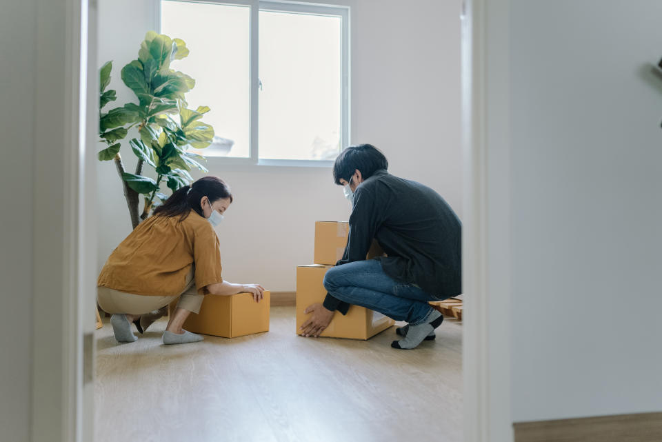 Happy man and woman carrying boxes together into their new home.