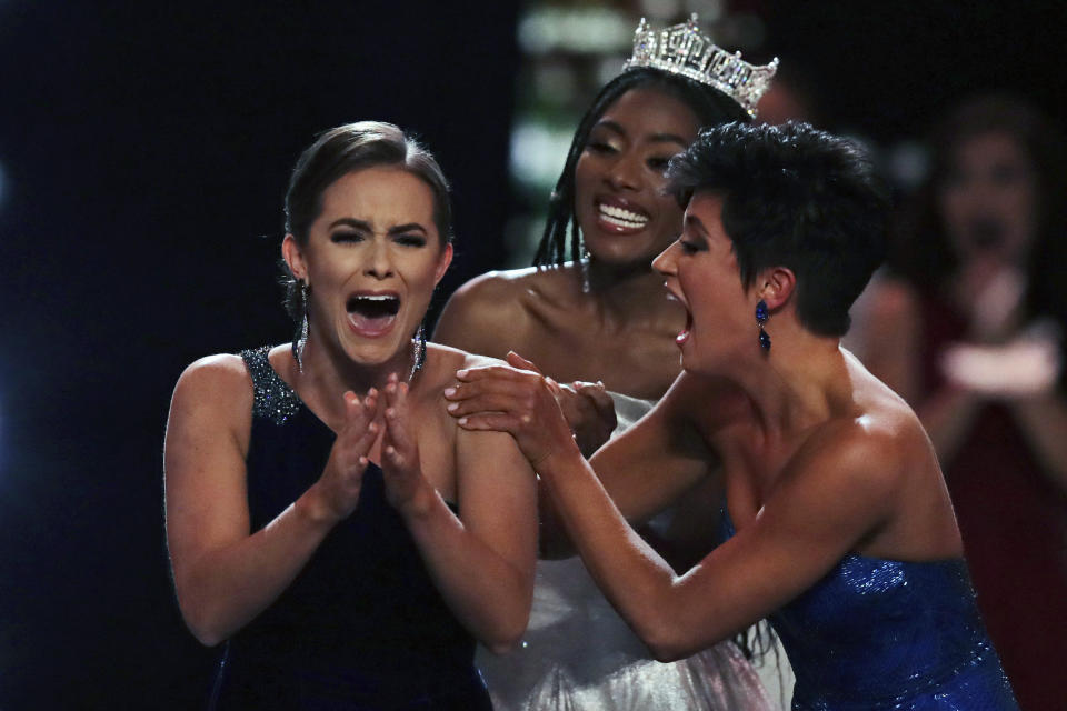 Camille Schrier, of Virginia, left, reacts after winning the Miss America competition at the Mohegan Sun casino in Uncasville, Conn., Thursday, Dec. 19, 2019. At right is runner-up Miss. Georgia Victoria Hill and and at rear is 2019 Miss. America Nia Franklin. (AP Photo/Charles Krupa)