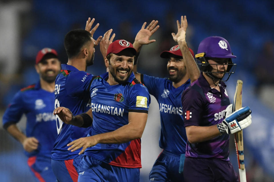 Afghanistan's players (pictured left) high-five and celebrate the dismissal of Scotland's Matthew Cross (pictured right).