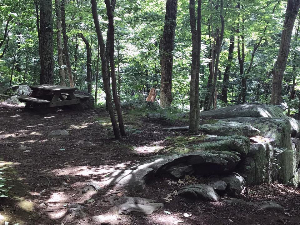 A picnic table is perched above a ledge at the top of a rugged hillside.