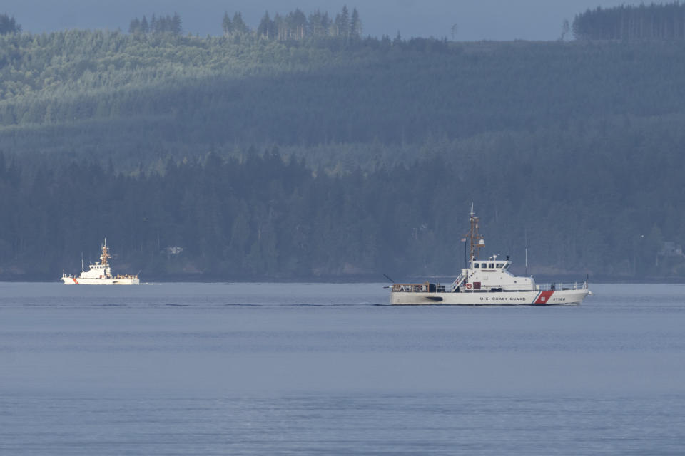 A pair of U.S. Coast Guard vessels searches the area, Monday, Sept. 5, 2022, near Freeland, Wash., on Whidbey Island north of Seattle where a chartered floatplane crashed the day before. The plane was carrying 10 people and was en route from Friday Harbor, Wash., to Renton, Wash. (AP Photo/Stephen Brashear)