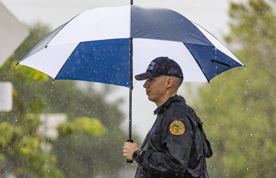 City of Miami police officer Ryan Dreseris helps direct traffic in heavy rain before the start of an event at the Bay of Pigs Memorial Park on Wednesday, April 12, 2023, in Miami. (Matias J. Ocner/Miami Herald via AP)
