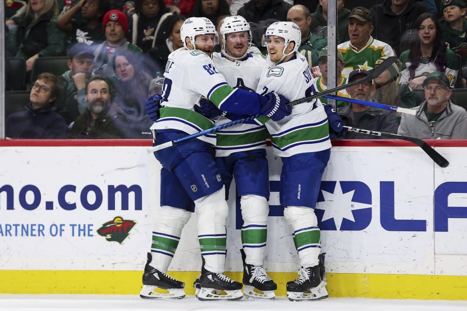 Vancouver Canucks center J.T. Miller is congratulated for his hat-trick by teammates defenseman Ian Cole and center Pius Suter during the second period of an NHL hockey game against the Minnesota Wild, Monday, Feb. 19, 2024, in St. Paul, Minn. (AP Photo/Matt Krohn)