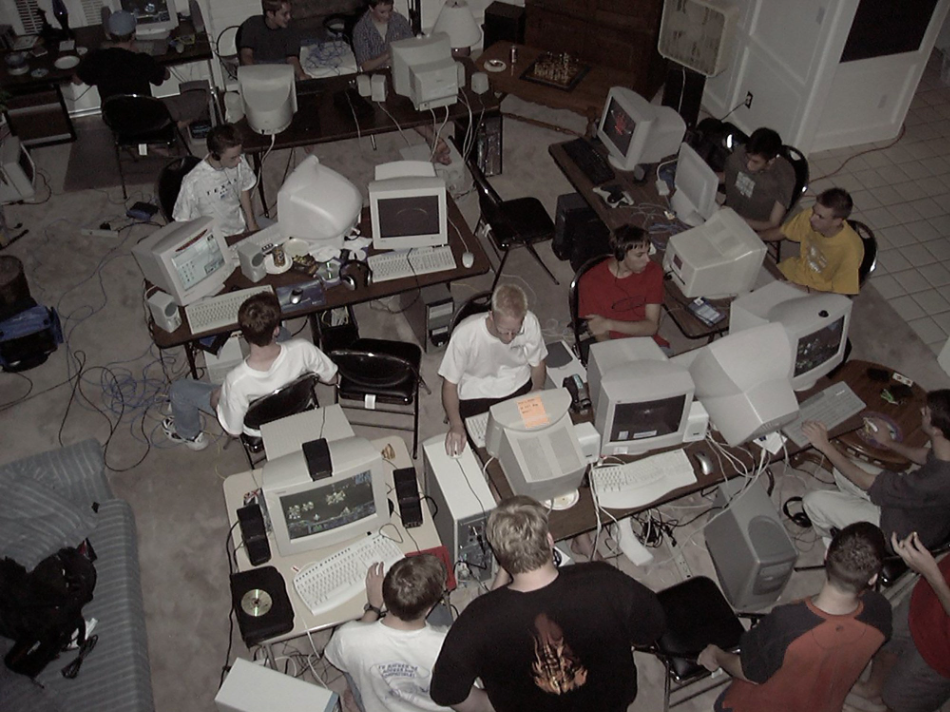 An aerial shot of an absolute squad of fellas sitting around huge monitor computers