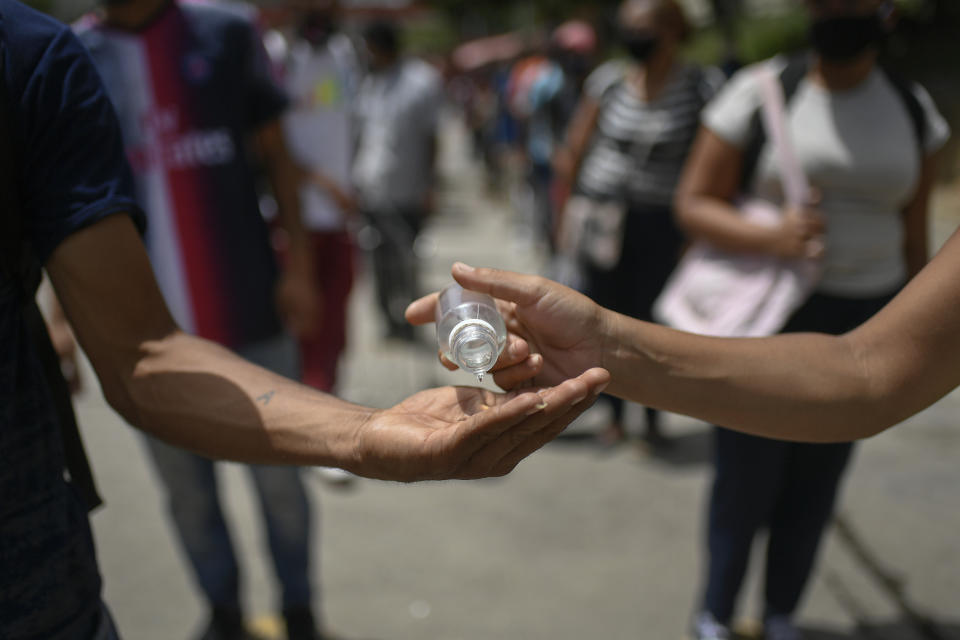 Una persona comparte gel desinfectante en Caracas, el sábado 11 de julio de 2020. (AP Foto/Matias Delacroix)