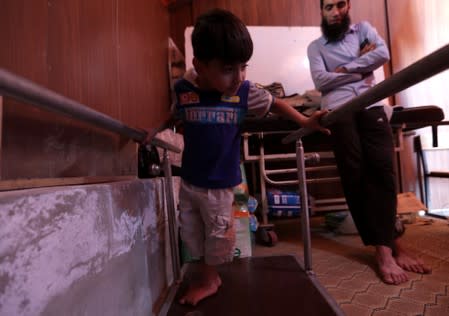 Displaced Syrian refugee boy attends a session at a physiotherapy clinic inside a large tent in the border village of Shamarin