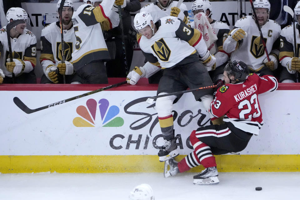 Vegas Golden Knights' Brayden McNabb (3) and Chicago Blackhawks' Philipp Kurashev collide in front of the Golden Knights bench during the third period of an NHL hockey game Thursday, Dec. 15, 2022, in Chicago. The Golden Knights won 4-1. (AP Photo/Charles Rex Arbogast)