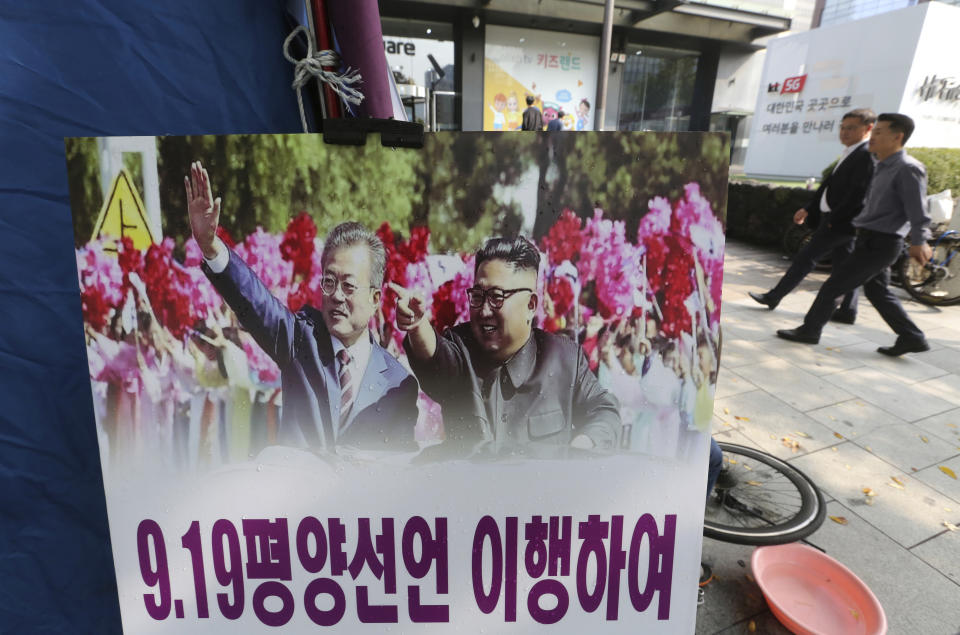 A photo showing South Korean President Moon Jae-in, left, and North Korean leader Kim Jong Un is displayed to wish for peace on the Korean Peninsula near the U.S. embassy in Seoul, South Korea, Tuesday, Oct. 23, 2018. The government of Moon formally approved the rapprochement deals he made with Kim last month. The sign reads: "Implementation of the Pyongyang Declaration on Sept. 19." (AP Photo/Ahn Young-joon)