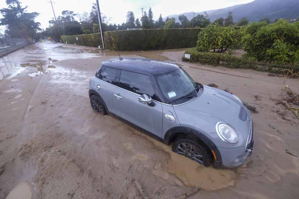 A vehicle is trapped by mud and debris at Jameson Lane near Highway 101 in Montecito, Calif., Tuesday, Jan. 10, 2023. California saw little relief from drenching rains Tuesday as the latest in a relentless string of storms swamped roads, turned rivers into gushing flood zones and forced thousands of people to flee from towns with histories of deadly mudslides. (AP Photo/Ringo H.W. Chiu)