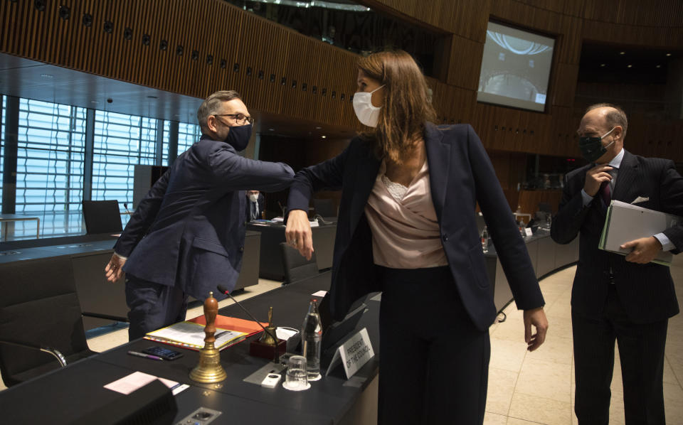 FILE - In this Oct.13, 2020 file photo Minister of State for Europe at the German Federal Foreign Office Michael Roth, left, greets Belgian Foreign Minister Sophie Wilmes with an elbow bump during a meeting of EU General Affairs ministers in Luxembourg. Former Belgian Prime minister Sophie Wilmes has been hospitalized in intensive care after getting infected with the coronavirus. The 45-year-old Wilmes, who was admitted to hospital on Wednesday evening Oct. 21, 2020, said last week she thought she got infected within her family circle. (AP Photo/Virginia Mayo, Pool, File)