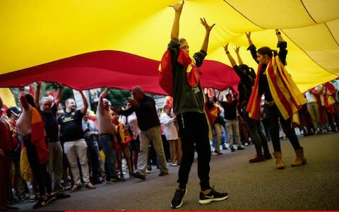 Anti-independence protesters carry a huge Spanish flag through the streets of Barcelona ahead of Catalonia's referendum on Sunday - Credit: Anadolu Agency 