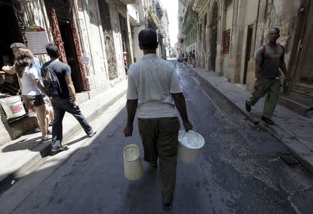 A man carries buckets of water in Havana in this April 13, 2011 file photo. REUTERS/Enrique De La Osa/Files