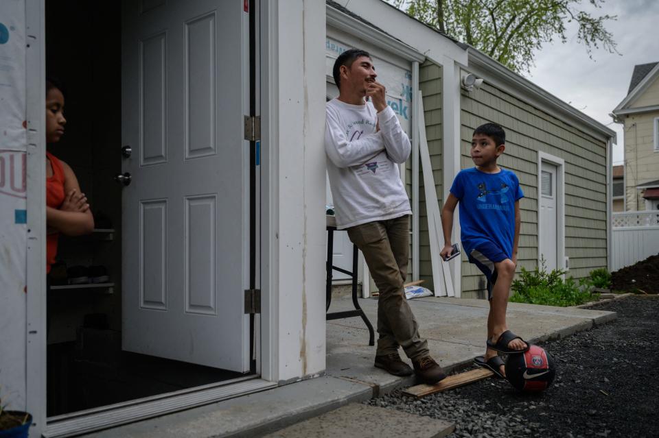 Valeriano (C), 34, an undocumented Guatemalan farmer who entered the US illegally at the end of March 2021 after being deported following his first attempt, stands at the entrance to the basement home he shares with his son Arnold (R) and his niece (L) in Hartford, Connecticut on April 29, 2021. / Credit: ED JONES/AFP via Getty Images