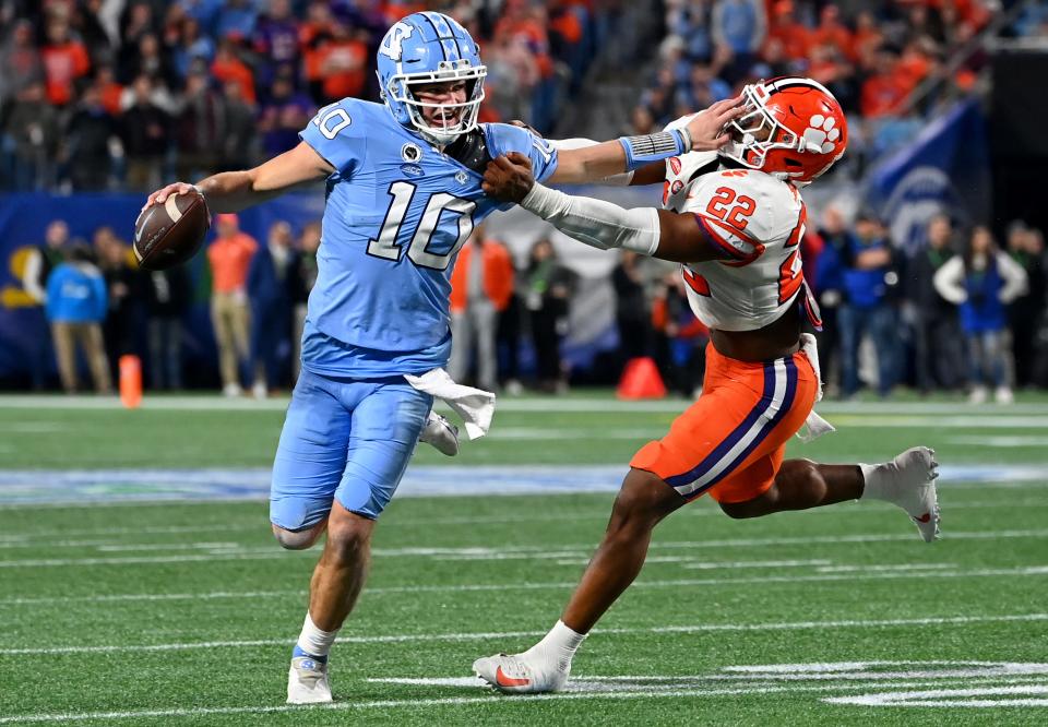 North Carolina Tar Heels quarterback Drake Maye (10) stiff arms Clemson Tigers linebacker Trenton Simpson (22) during the second quarter of the ACC Championship game at Bank of America Stadium.