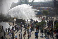 Policemen use water cannon to prevent protesting farmers from moving ahead towards Delhi, at the border between Delhi and Haryana state, Friday, Nov. 27, 2020. Thousands of agitating farmers in India faced tear gas and baton charge from police on Friday after they resumed their march to the capital against new farming laws that they fear will give more power to corporations and reduce their earnings. While trying to march towards New Delhi, the farmers, using their tractors, cleared concrete blockades, walls of shipping containers and horizontally parked trucks after police had set them up as barricades and dug trenches on highways to block roads leading to the capital. (AP Photo)