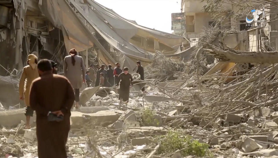 FILE - This undated file frame grab from video posted online Monday, May 29, 2017, by the Aamaq News Agency, a media arm of the Islamic State group, shows people inspecting damage from airstrikes and artillery shelling in the northern Syrian city of Raqqa, the de facto capital of the IS. With Islamic State's near total defeat on the battle field, the extremist group has reverted to what it was before its spectacular series of conquests in 2014 _ a shadowy terror network that targets vulnerable civilian populations and exploits state weaknesses to incite on sectarian strife. But a recent surge in false claims of responsibility for attacks also signals that the group is struggling to stay relevant after losing its proto-state and its dominance of the international news agenda. (Aamaq News Agency via AP, File)