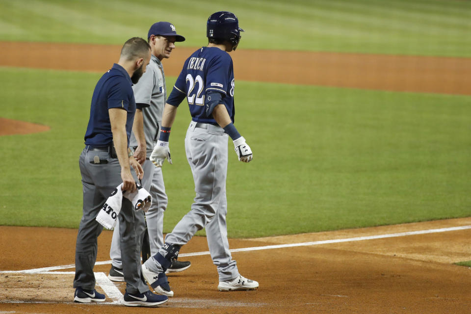 Milwaukee Brewers' Christian Yelich (22) walks off the field with a trainer and manager Craig Counsell, center, after an injury during the first inning of the team's baseball game against the Miami Marlins, Tuesday, Sept. 10, 2019, in Miami. Yelich broke his right kneecap on a foul ball and will miss the rest of the regular season. (AP Photo/Wilfredo Lee)