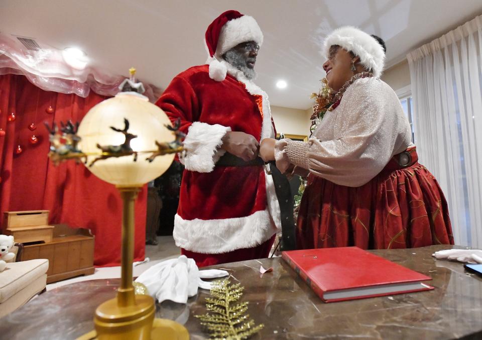 Shawn Coley gets an assist with his Santa suit from his wife Natasha Spencer-Coley as they prepare for their first Selfies with Santa session on December 15 at their Ft. Caroline Road area home.