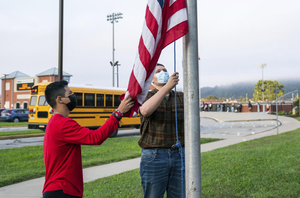 From left, 11th grader Ricardo Lopez, and 10th grader Justin Couch, raise the flag as a part of ROTC's flag detail outside at Ambridge Area Senior High School on the first day of Pennsylvania's mask mandate for K-12 schools and day care centers on Tuesday, Sept. 7, 2021, in Ambridge, Pa. (Andrew Rush /Pittsburgh Post-Gazette via AP)