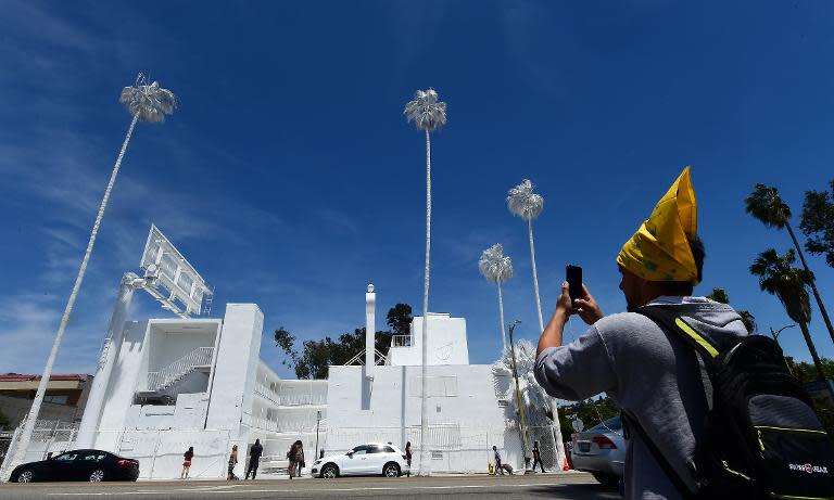 A passer-by photographs 'Projection', a public art project of French installation artist Vincent Lamouroux, drawing attention with everything painted white to a forgotten Los Angeles landmark, Bates Motel, on April 26, 2015