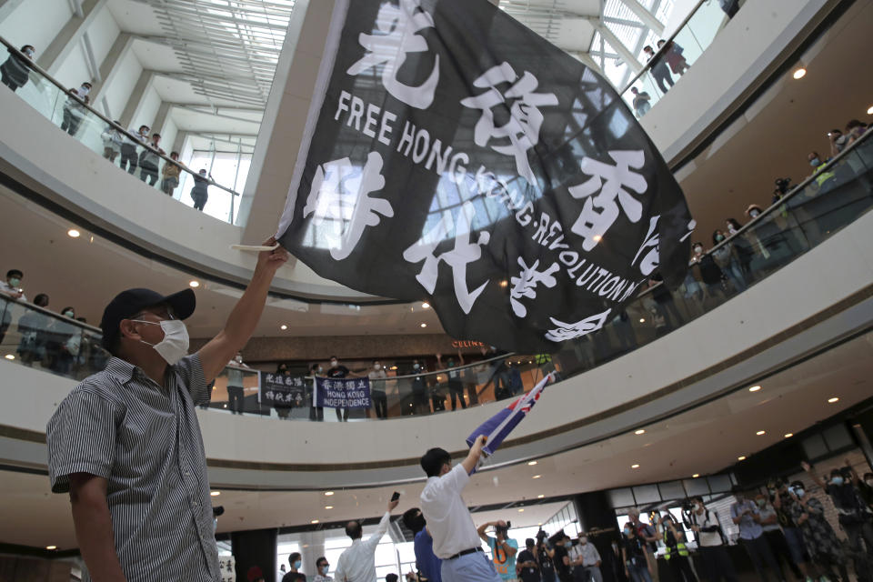 Protesters wave flags in a shopping mall during a protest against China's national security legislation for the city, in Hong Kong, Friday, May 29, 2020. The British government says t it will grant hundreds of thousands of Hong Kong residents greater visa rights if China doesn't scrap a planned new security law for the semi-autonomous territory. U.K. Foreign Secretary Dominic Raab said about 300,000 people in Hong Kong who hold British National (Overseas) passports will be able to stay in Britain for 12 months rather than the current six. (AP Photo/Kin Cheung)