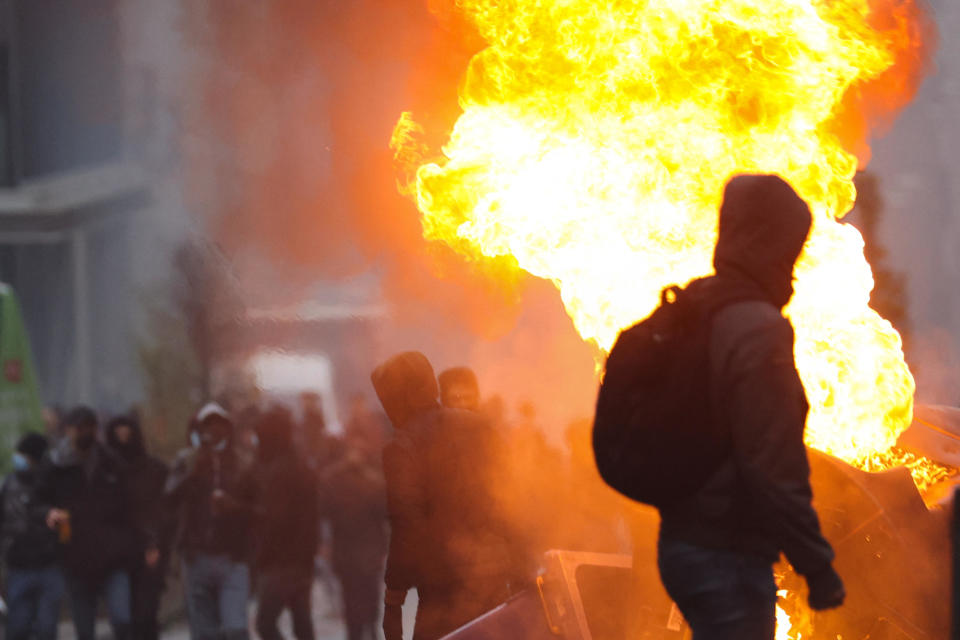 A man walks in front of burning trash amid clashes with police during a demonstration against the government's anti-COVID-19 measures, including the country's digital health pass, in Brussels, Belgium, November 21, 2021. / Credit: KENZO TRIBOUILLARD/AFP/Getty