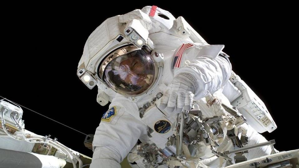  An astronaut in a spacesuit floats in zero gravity against the blackness of space. 