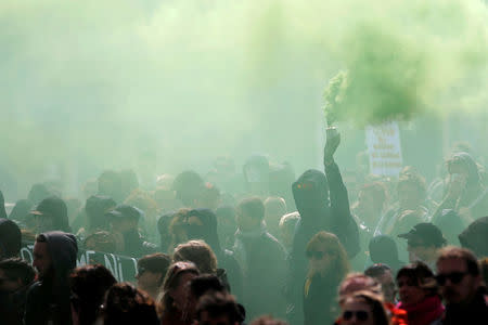 A demonstrator holds a warning flare as part of traditional May Day labour day march in Nantes, France. REUTERS/Stephane Mahe