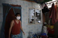 Christopher Bagay, left, a kitchen crew of the Aida Sol cruise ship in Europe, walks outside their house as his wife, right, continues her work from home duty at their house in Laguna province, south of Manila, Philippines Thursday, May 28, 2020. Bagay said it took him about two months to go through repetitive quarantines in Spain, Germany and Manila before he was finally allowed to go home. Tens of thousands of workers have returned by plane and ships as the pandemic, lockdowns and economic downturns decimated jobs worldwide in a major blow to the Philippines, a leading source of global labor. (AP Photo/Aaron Favila)