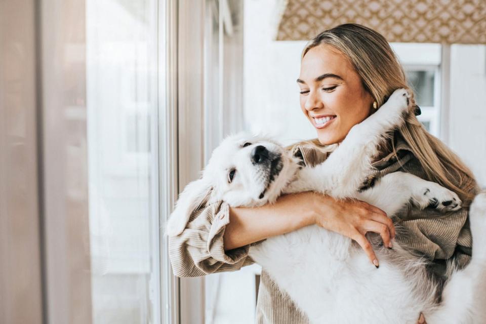 woman holding puppy; what to consider before adopting a dog